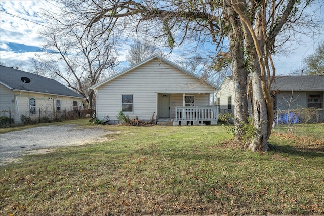 back of property featuring covered porch, a yard, and fence