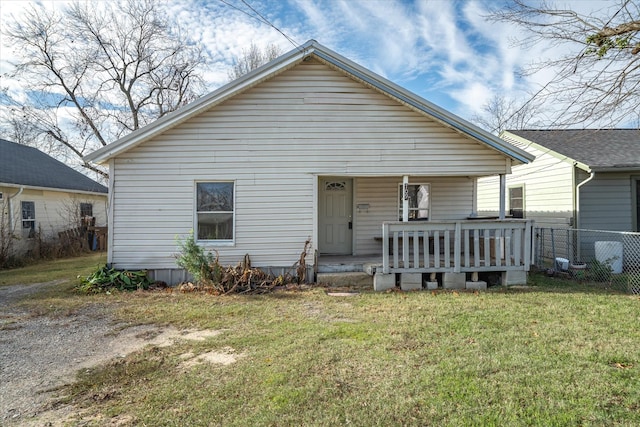bungalow-style house featuring covered porch, fence, and a front lawn