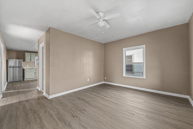 unfurnished room featuring baseboards, a ceiling fan, and wood finished floors