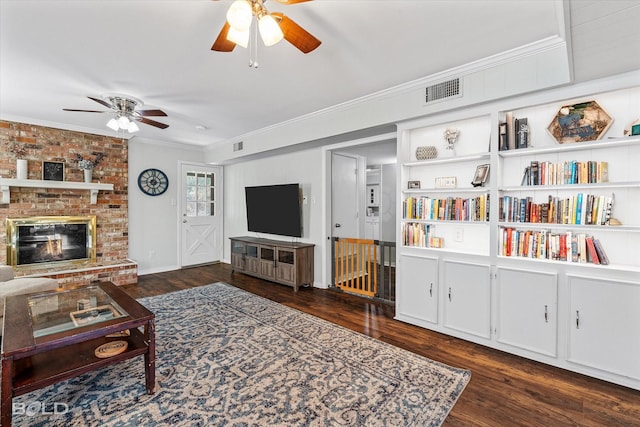 living room featuring crown molding, a brick fireplace, dark hardwood / wood-style floors, ceiling fan, and built in features