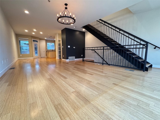 unfurnished living room featuring a notable chandelier and light hardwood / wood-style floors