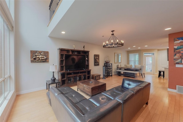 living room with light wood-type flooring and an inviting chandelier