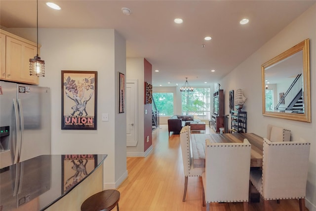 dining space with light hardwood / wood-style flooring and a chandelier