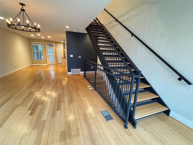 stairway featuring wood-type flooring and a chandelier