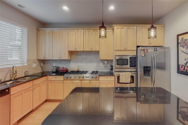 kitchen featuring backsplash, stainless steel appliances, sink, pendant lighting, and light hardwood / wood-style flooring