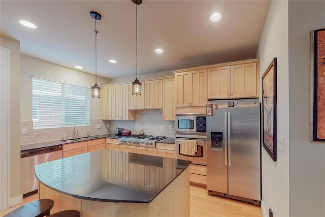 kitchen with hanging light fixtures, sink, a kitchen island, and stainless steel appliances