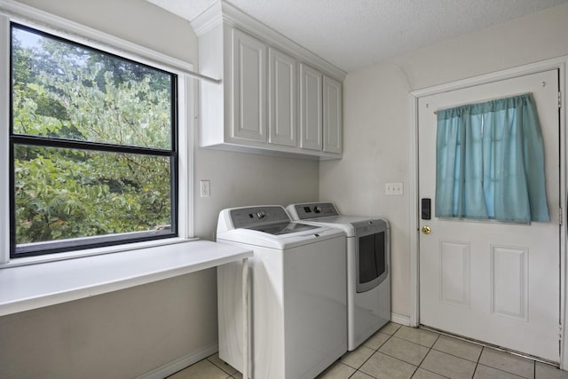 laundry area with light tile patterned floors, cabinets, a textured ceiling, and independent washer and dryer