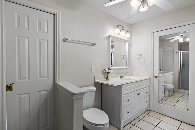 bathroom with tile patterned flooring, vanity, a textured ceiling, and toilet