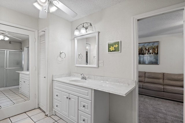 bathroom featuring ceiling fan, tile patterned floors, a textured ceiling, a shower with door, and vanity