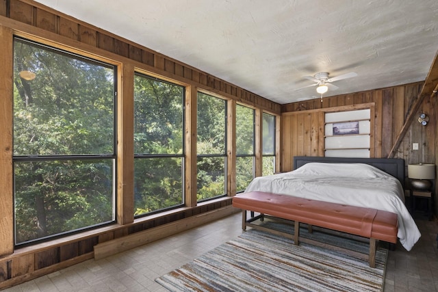 bedroom featuring ceiling fan and wooden walls