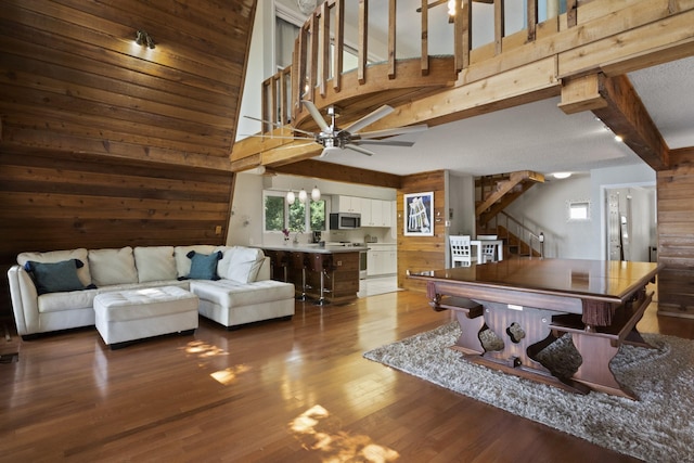 rec room with beam ceiling, high vaulted ceiling, ceiling fan, and wooden walls