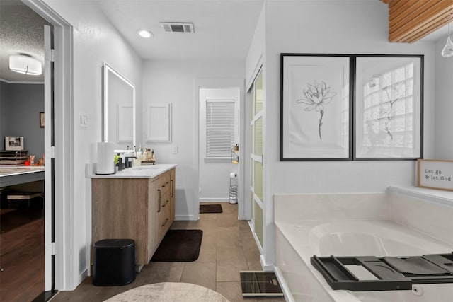 bathroom featuring a tub to relax in, tile patterned floors, vanity, and a textured ceiling