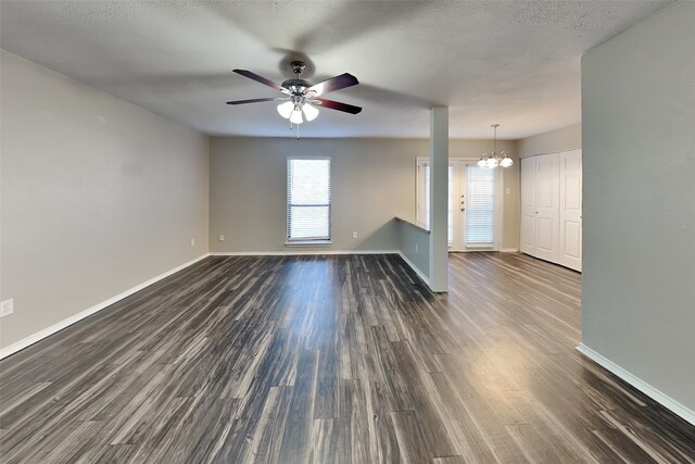 spare room featuring a textured ceiling, ceiling fan with notable chandelier, and dark wood-type flooring