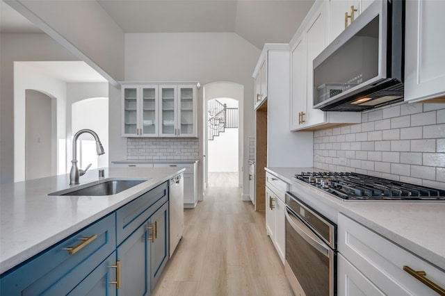 kitchen featuring backsplash, white cabinets, sink, blue cabinetry, and appliances with stainless steel finishes