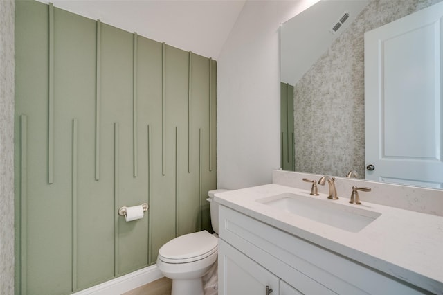 bathroom featuring vanity, toilet, and lofted ceiling