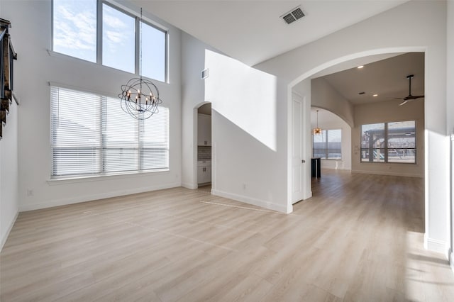 unfurnished living room featuring light wood-type flooring and ceiling fan with notable chandelier