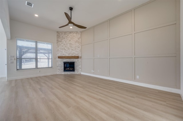 unfurnished living room featuring ceiling fan, a fireplace, and light wood-type flooring