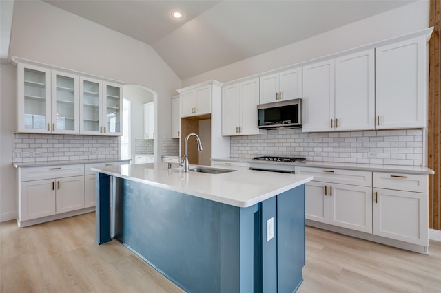 kitchen featuring sink, white cabinetry, vaulted ceiling, and an island with sink