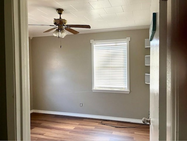 spare room with ceiling fan, ornamental molding, and light wood-type flooring