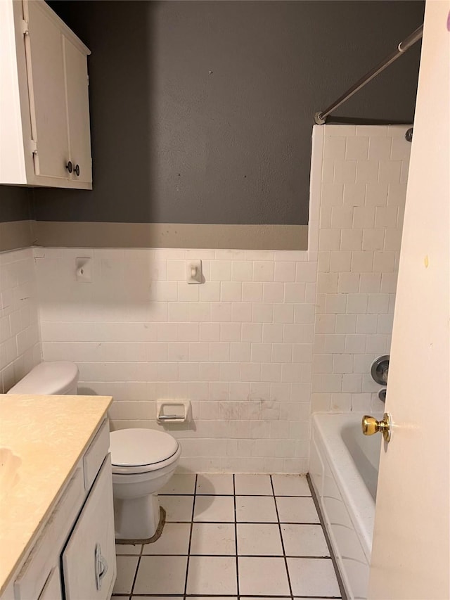 full bathroom featuring tile patterned flooring, toilet, shower / washtub combination, vanity, and tile walls