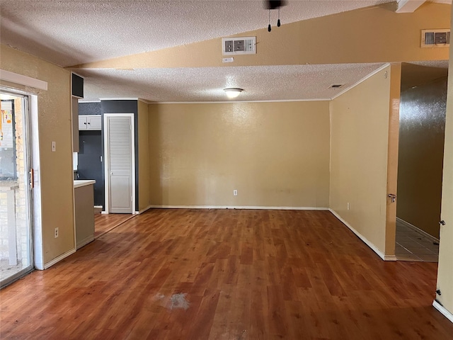 unfurnished room with dark hardwood / wood-style flooring, a textured ceiling, and vaulted ceiling