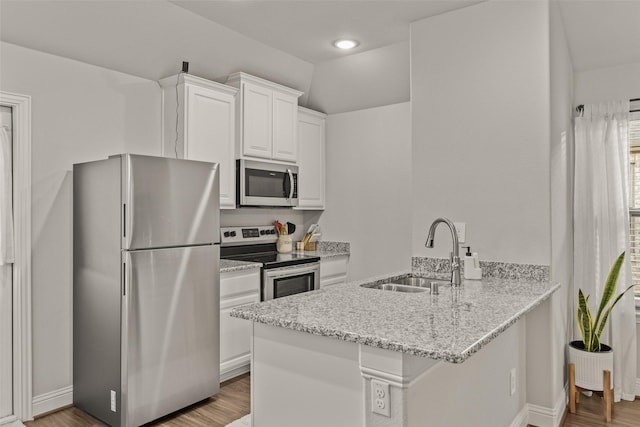 kitchen with sink, stainless steel appliances, light stone counters, white cabinets, and kitchen peninsula