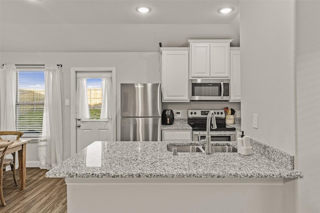 kitchen featuring appliances with stainless steel finishes, white cabinetry, sink, light stone countertops, and light wood-type flooring