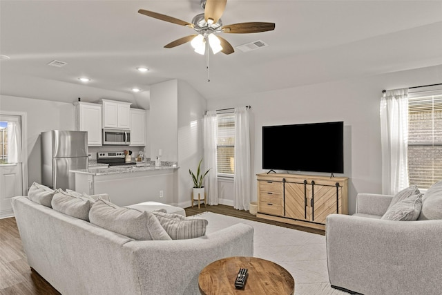 living room featuring ceiling fan, a healthy amount of sunlight, and light wood-type flooring