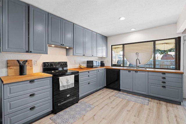 kitchen with sink, wooden counters, gray cabinets, black appliances, and light wood-type flooring