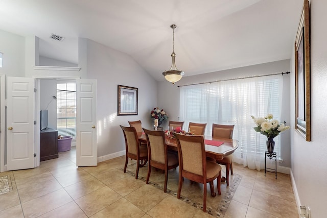 tiled dining space featuring vaulted ceiling