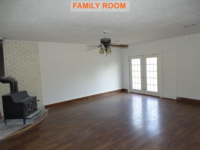 unfurnished living room with dark wood-type flooring, french doors, a textured ceiling, a wood stove, and ceiling fan