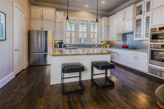 kitchen featuring light stone countertops, a breakfast bar, stainless steel appliances, pendant lighting, and a kitchen island