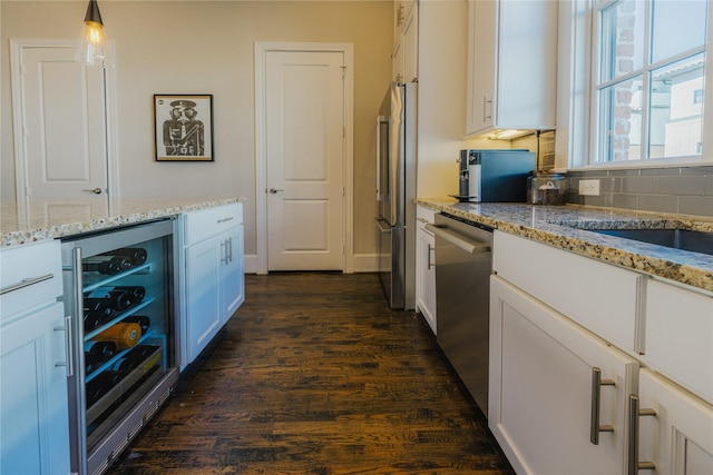 kitchen featuring hanging light fixtures, dark hardwood / wood-style floors, appliances with stainless steel finishes, white cabinetry, and beverage cooler