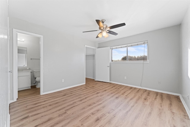 unfurnished bedroom featuring ceiling fan, a spacious closet, connected bathroom, light hardwood / wood-style floors, and a closet