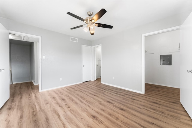 unfurnished bedroom featuring a walk in closet, electric panel, light hardwood / wood-style flooring, and ceiling fan