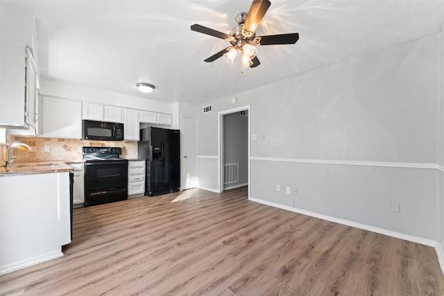 kitchen featuring white cabinetry, sink, decorative backsplash, black appliances, and light wood-type flooring