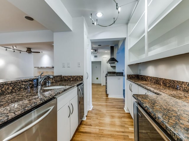 kitchen featuring white cabinets, wall chimney exhaust hood, ceiling fan, and stainless steel dishwasher