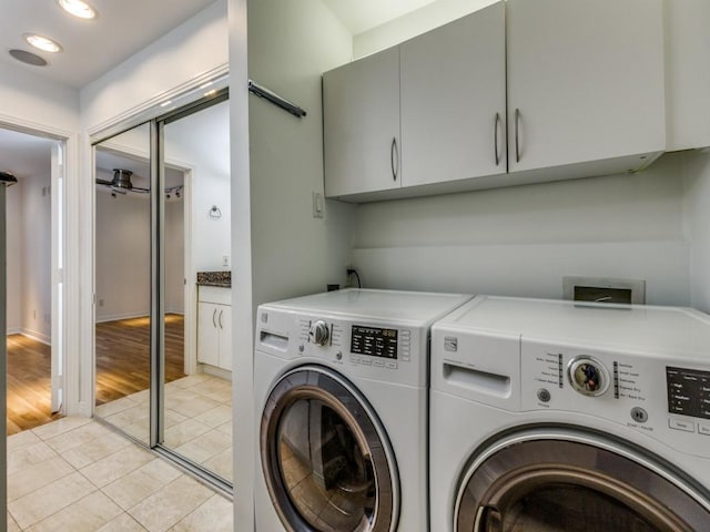 laundry area with cabinets, light tile patterned floors, and washing machine and clothes dryer