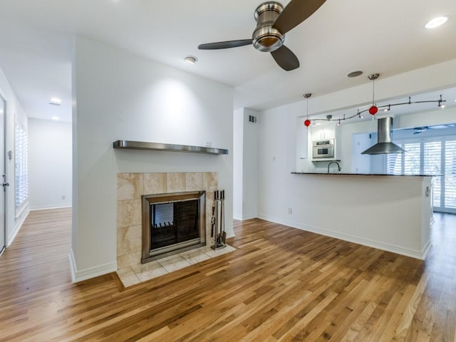 unfurnished living room with ceiling fan, a fireplace, and light hardwood / wood-style flooring