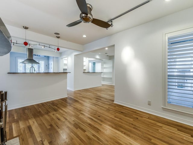 unfurnished living room with wood-type flooring, ceiling fan, and sink