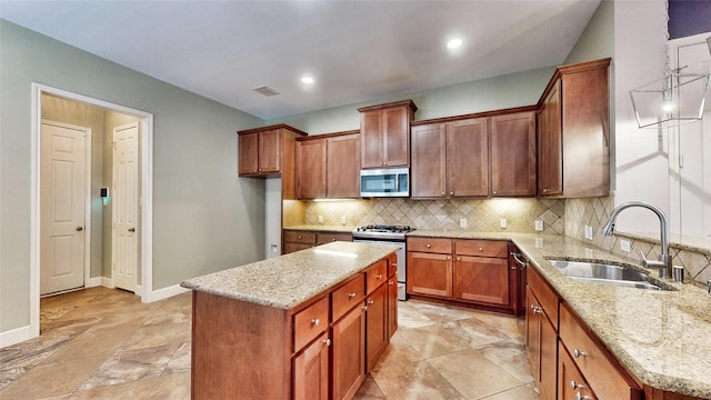 kitchen with a center island, light stone counters, sink, and appliances with stainless steel finishes