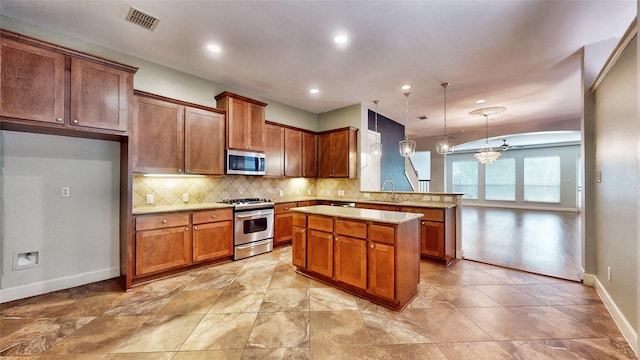 kitchen with decorative light fixtures, decorative backsplash, appliances with stainless steel finishes, a notable chandelier, and kitchen peninsula