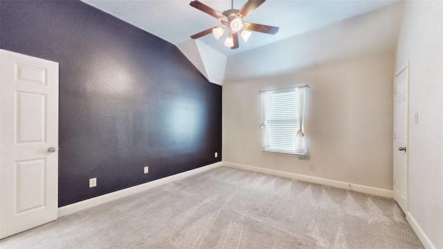 carpeted spare room with ceiling fan and vaulted ceiling