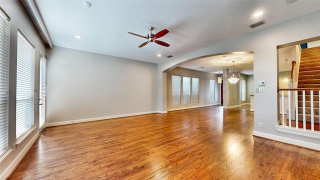 unfurnished living room featuring hardwood / wood-style floors and ceiling fan with notable chandelier