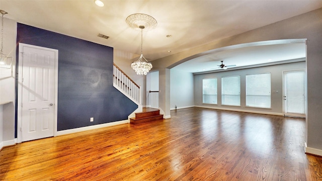 unfurnished living room featuring ceiling fan with notable chandelier and hardwood / wood-style flooring