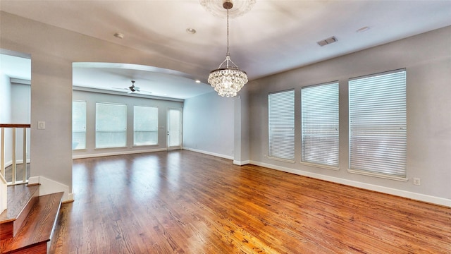 unfurnished living room featuring wood-type flooring and ceiling fan with notable chandelier