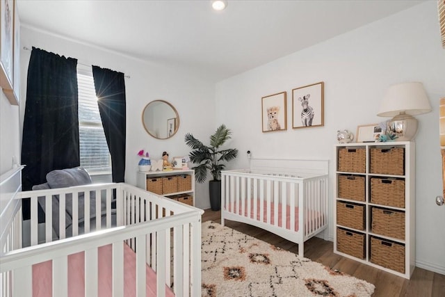 bedroom with a crib and hardwood / wood-style floors