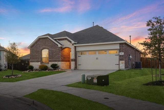 view of front of house featuring a garage, a lawn, and central AC