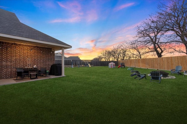 yard at dusk featuring a patio and a playground