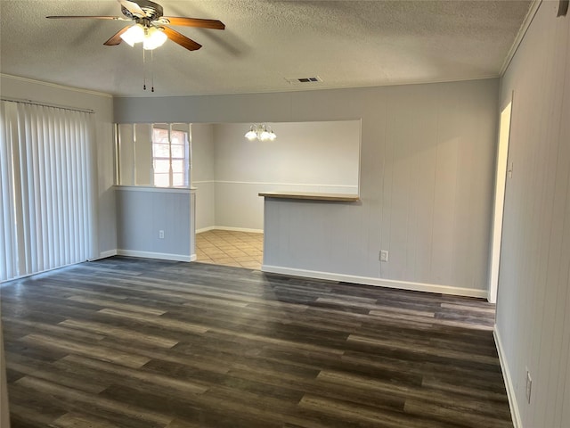 unfurnished room with ceiling fan with notable chandelier, dark hardwood / wood-style flooring, ornamental molding, and a textured ceiling